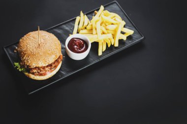 Lezzetli çizburger ve patates kızartması siyah arka plan üzerine