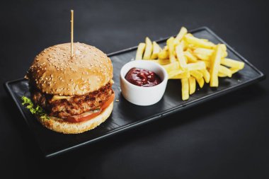 Lezzetli çizburger ve patates kızartması siyah arka plan üzerine