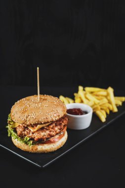 Lezzetli çizburger ve patates kızartması siyah arka plan üzerine