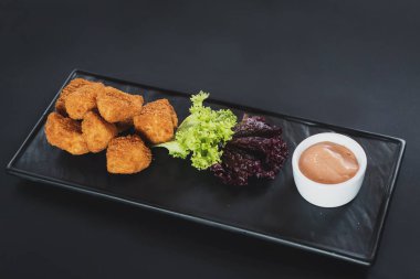 Siyah arka plan üzerine soslu kızarmış balık parçaları. Kopya alanı