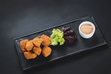 Siyah arka plan üzerine soslu kızarmış balık parçaları. Kopya alanı