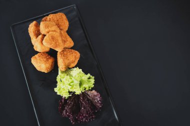 Siyah arka plan üzerine soslu kızarmış balık parçaları. Kopya alanı