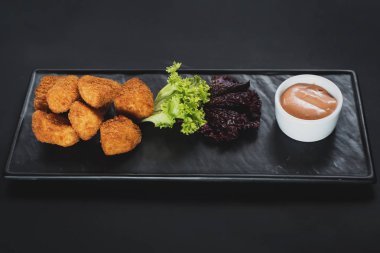 Siyah arka plan üzerine soslu kızarmış balık parçaları. Kopya alanı