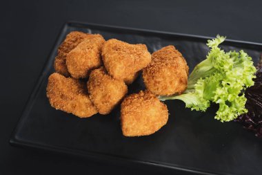 Siyah arka plan üzerine soslu kızarmış balık parçaları. Kopya alanı