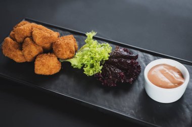 Siyah arka plan üzerine soslu kızarmış balık parçaları. Kopya alanı