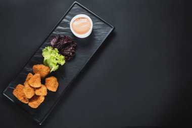 Siyah arka plan üzerine soslu kızarmış balık parçaları. Kopya alanı