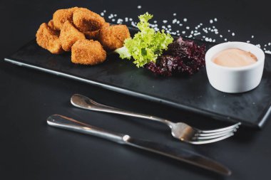 Siyah arka plan üzerine soslu kızarmış balık parçaları. Kopya alanı