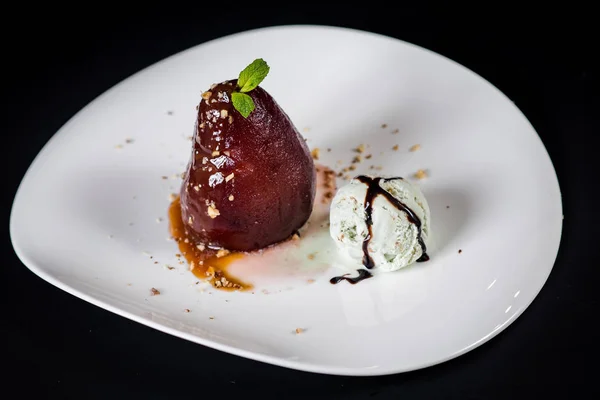 A dessert with caramelized pear and ice on black background