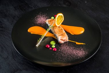 Siyah plaka üzerinde soslu somon balığı ızgara parça