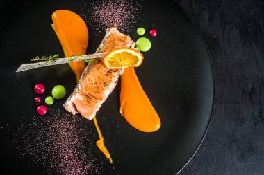 Siyah plaka üzerinde soslu somon balığı ızgara parça