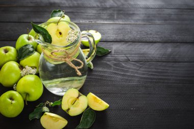 Siyah ahşap arka planda elmalarla dolu cam bir su kavanozu. Uzayı kopyala Sağlıklı yemek, detoks.