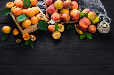 Siyah ahşap arka planda taze kayısılar ve erikler. Boşluğu kopyala