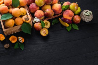 Siyah ahşap arka planda taze kayısılar ve erikler. Boşluğu kopyala