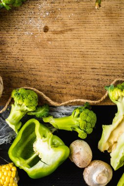 Ahşap arka planda bir sürü yeşil olgun sebze var. Boşluğu kopyala