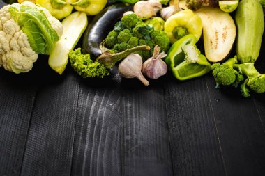 Ahşap arka planda bir sürü yeşil olgun sebze var. Boşluğu kopyala