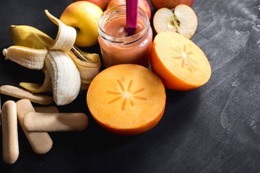 Sağlıklı yiyecekler. Meyveli yoğurt ya da camda püre ve siyah arka planda farklı meyveler. Üst Manzara. Boşluğu kopyala