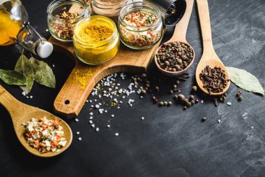 Farklı baharatlar ve siyah arkaplana saçılmış gıda malzemeleri.