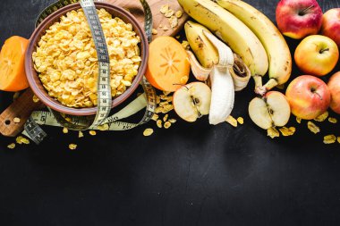 Siyah arka planda mısır gevreği ve meyveli bir tabak. Sağlıklı yiyecekler. Boşluğu kopyala