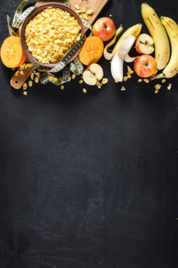 Siyah arka planda mısır gevreği ve meyveli bir tabak. Sağlıklı yiyecekler. Boşluğu kopyala