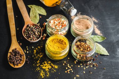 Bardaktaki farklı baharatlar ve siyahtaki yemek malzemeleri. Boşluğu kopyala