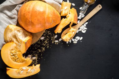 Siyah ahşap arka planda kesilmiş büyük çiğ balkabağı. Boşluğu kopyala