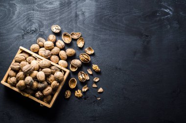 Siyah arka planda tahta kutuda bir sürü kuru fındık var. Boşluğu kopyala