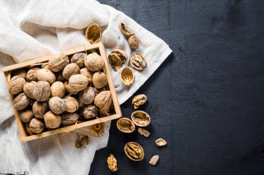 Siyah arka planda tahta kutuda bir sürü kuru fındık var. Boşluğu kopyala