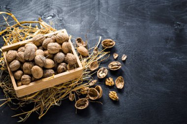 Siyah arka planda tahta kutuda bir sürü kuru fındık var. Boşluğu kopyala