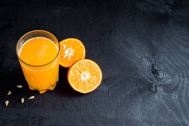 Siyah arka planda çiğ portakallı portakal suyu. Boşluğu kopyala