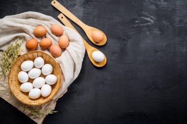 Siyah ahşap arka planda sepetteki tavuk yumurtaları. Boşluğu kopyala