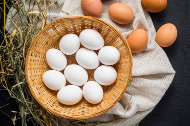 Siyah ahşap arka planda sepetteki tavuk yumurtaları. Boşluğu kopyala