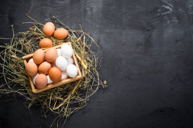 Siyah arka planda tahta kutuda farklı tavuk yumurtaları. Boşluğu kopyala