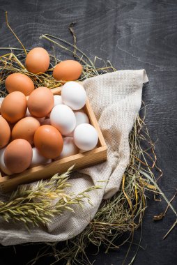 Siyah arka planda tahta kutuda farklı tavuk yumurtaları. Boşluğu kopyala