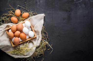 Siyah arka planda tahta kutuda farklı tavuk yumurtaları. Boşluğu kopyala
