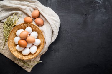 Siyah ahşap arka planda sepetteki tavuk yumurtaları. Boşluğu kopyala