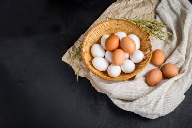 Siyah ahşap arka planda sepetteki tavuk yumurtaları. Boşluğu kopyala
