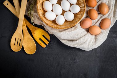 Siyah ahşap arka planda sepetteki tavuk yumurtaları. Boşluğu kopyala