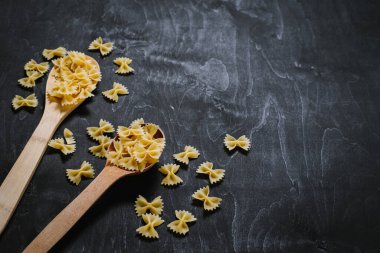 Siyah arka planda kelebek şeklinde çiğ makarna. Boşluğu kopyala