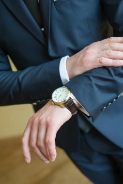 Takım elbiseli bir adam saatlerine bakıyor.