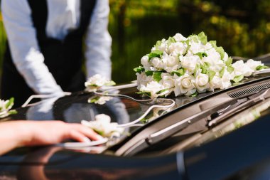 Düğün gününde bir arabayı çiçeklerle süsleyen insanlar.