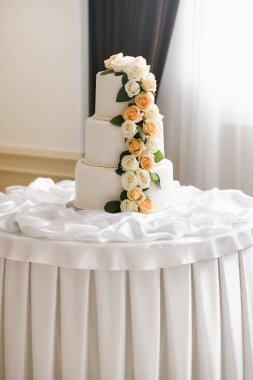 Güllerle süslenmiş büyük beyaz düğün pastası