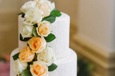 Güllerle süslenmiş büyük beyaz düğün pastası