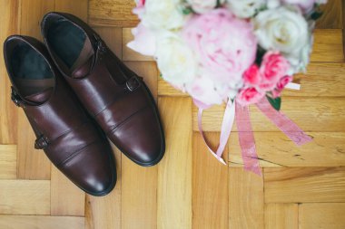 Ahşap arka planda damat ayakkabıları ve buket
