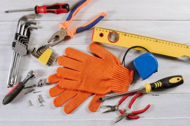 Beyaz ahşap arka planda farklı bina ya da zanaat araçları ve eldivenler düzleştirilmiş