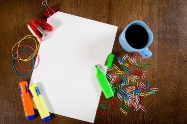 Masanın üzerinde bir fincan kahve ve farklı ofis aletleri olan boş beyaz bir kağıt.