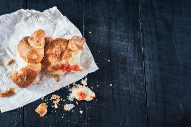 Siyah ahşap arka planda reçelli ezilmiş kruvasan.