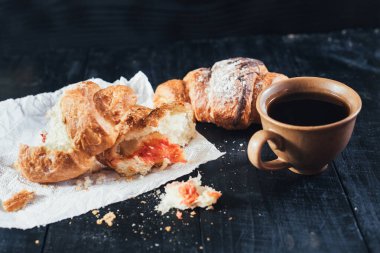 Siyah ahşap arka planda tatlı kruvasanlar ve bir fincan kahve. Boşluğu kopyala