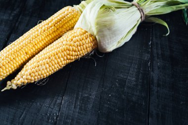 Siyah arka planda çiğ mısır. Boşluğu kopyala