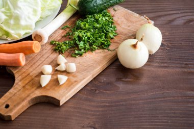 Tahtadaki diğer sebzelerle birlikte doğranmış soğan ve otlar. Yemek hazırlığı