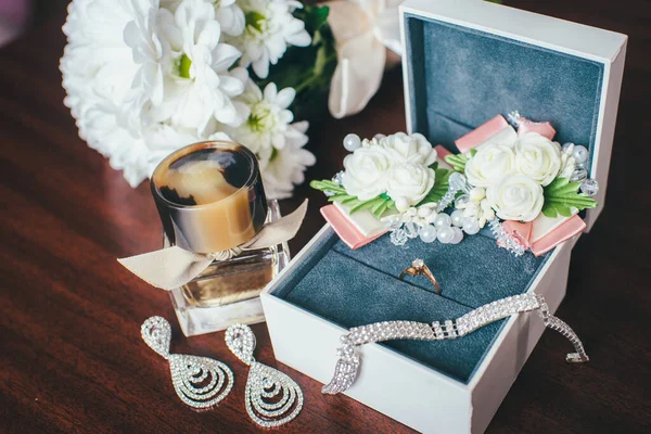 Beautiful shiny jewelry and flowers on wooden background